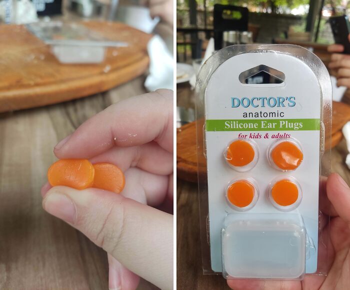 Orange silicone ear plugs held in a hand and shown in retail packaging on a wooden table background.