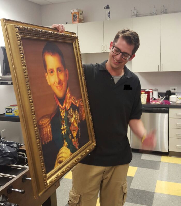 Employee holding a humorous framed portrait prank in an office kitchen illustrating employees with jokes and pranks.