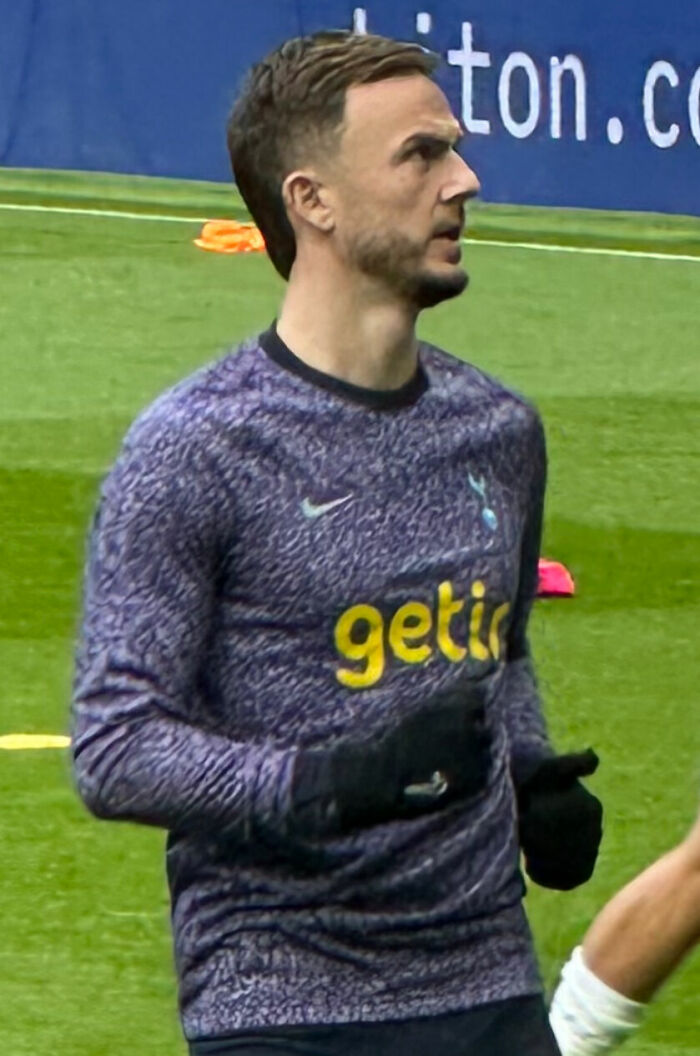 James Maddison warming up on the field wearing a purple training top and black gloves during a soccer session.