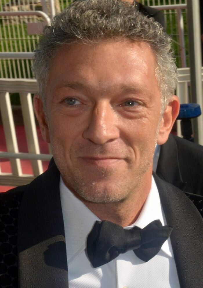 Vincent Cassel smiling, dressed in a tuxedo with a bow tie at a formal event, showcasing his career highlights.