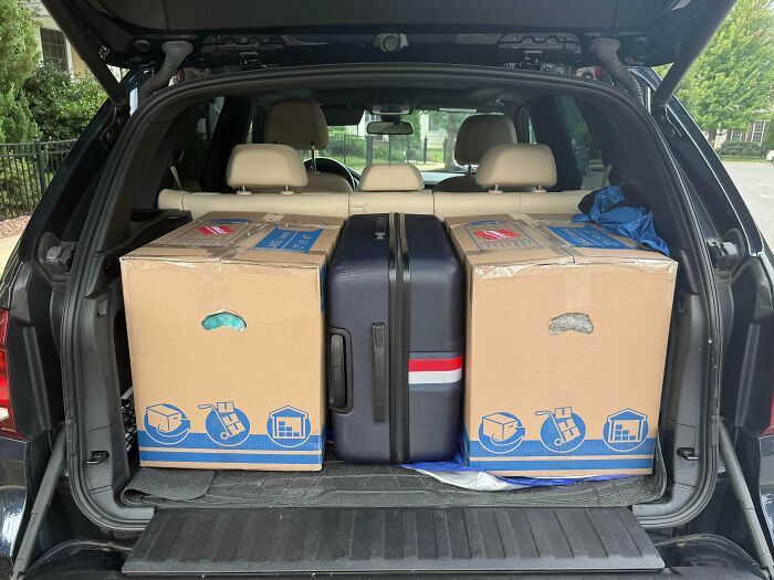 Two cardboard boxes perfectly aligned on either side of a suitcase in the trunk, showing flawless alignment.