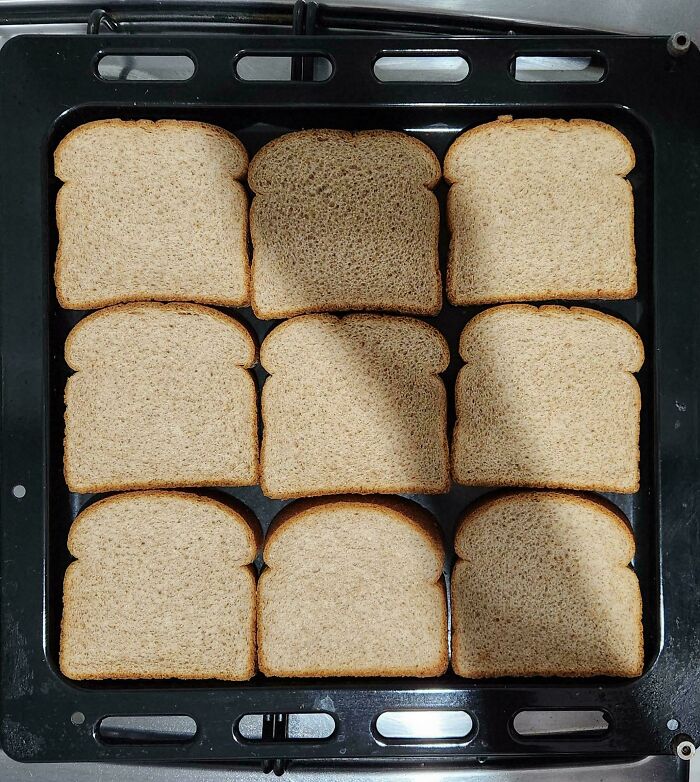 Slices of bread perfectly aligned in a black tray creating a visually satisfying pattern for alignment enthusiasts.