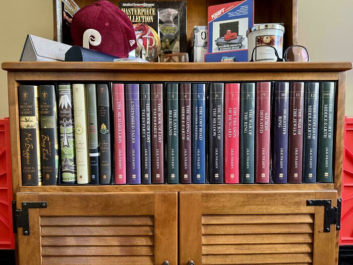 A perfectly aligned collection of Lord of the Rings books neatly arranged on a wooden shelf.