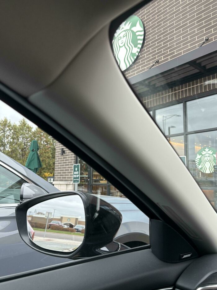 View from car interior perfect alignment of Starbucks logos and order pickup sign outside a coffee shop.