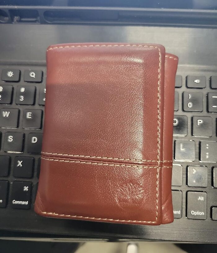 Brown leather wallet on black keyboard, ideal for Black Friday deals on stocking stuffers to save money.