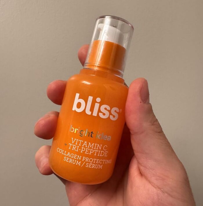 Hand holding orange Bliss Vitamin C Tri-Peptide collagen protecting serum, a popular Black Friday stocking stuffer deal.
