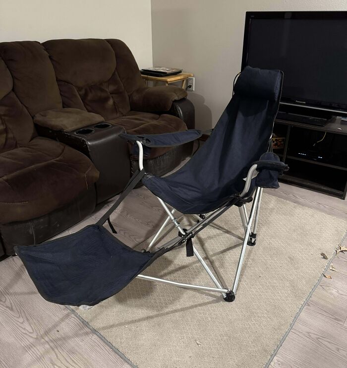 Collapsible reclining chair with footrest set up indoors near a brown couch and television, showcasing redneck engineer creativity.