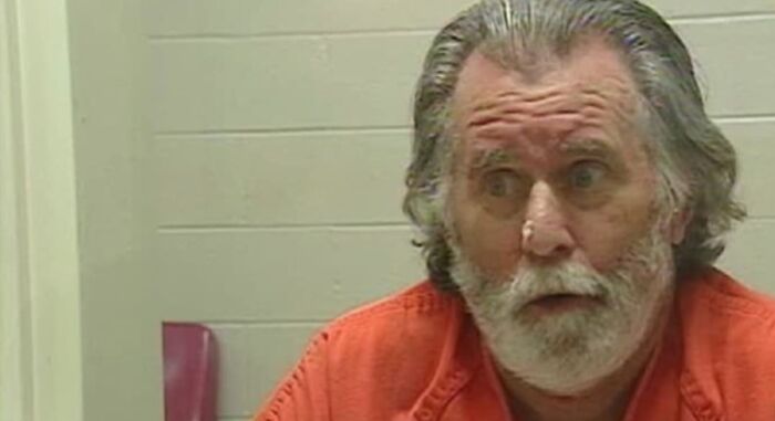 Older man with gray hair and beard wearing an orange jumpsuit, looking surprised in a strange world facts story setting