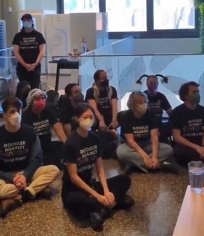 Group of people wearing masks and "Googler Against" shirts sitting indoors, highlighting strange world facts and stories.