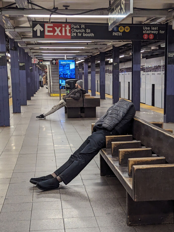 Man in jacket leaning back at an impossible angle on subway bench, a confusing photo challenging your brain to catch up.