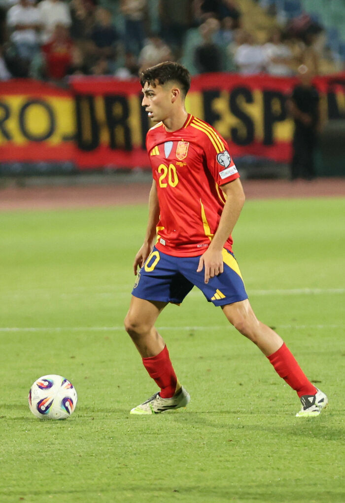 Pedri in Spanish national team uniform controlling ball on the field during an international soccer match.