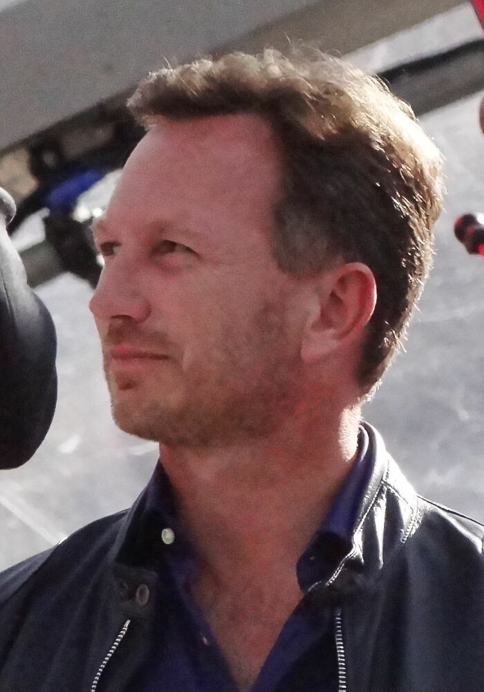 Christian Horner in casual attire looking sideways, captured outdoors in natural lighting.