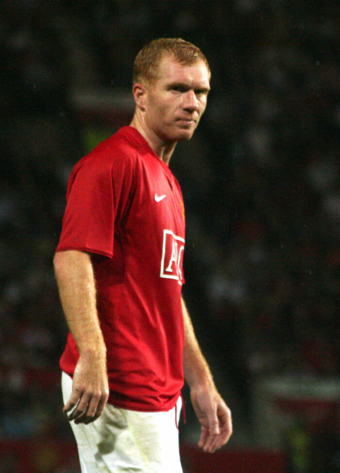 Paul Scholes in a Manchester United red jersey on the field during a soccer match, focused and ready to play.