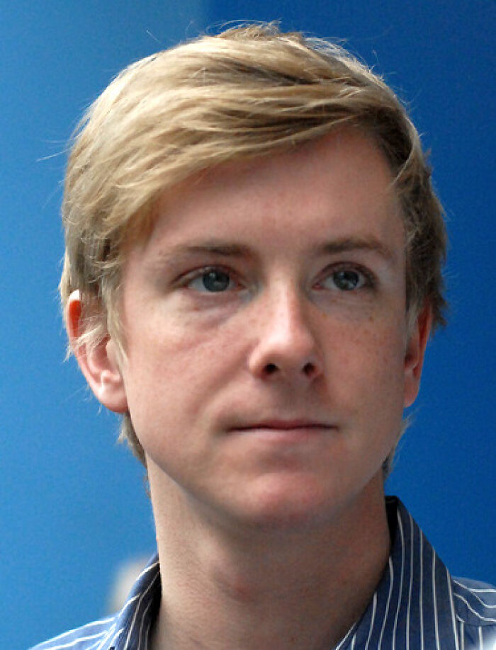 Chris Hughes with blond hair and blue eyes, wearing a striped shirt, against a blue background for bio and career highlights.