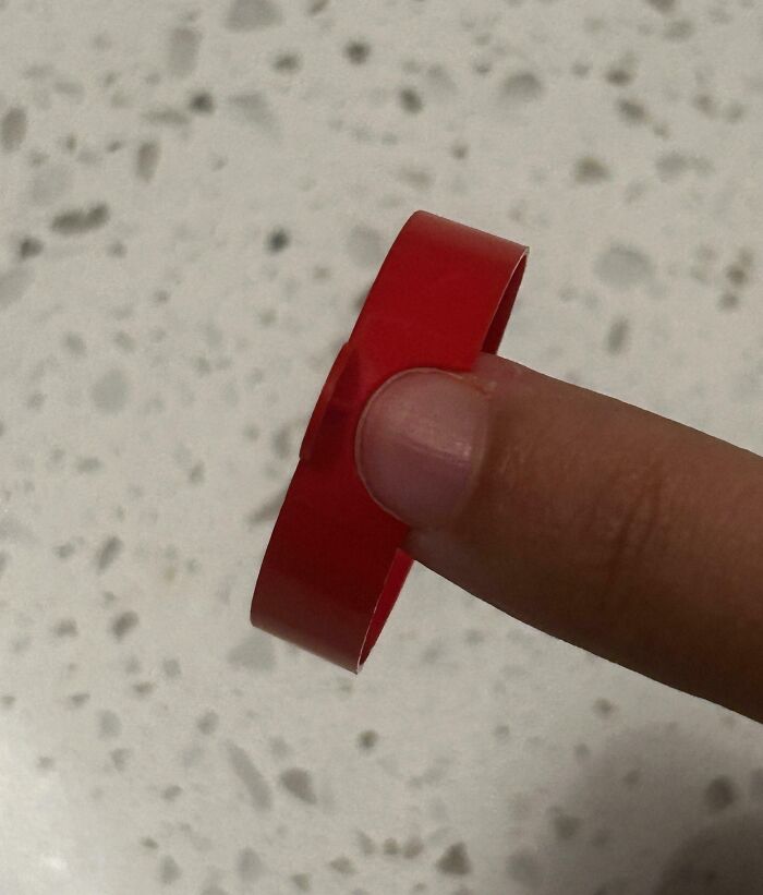 Red sticker perfectly aligned and balanced on a fingertip, showcasing things aligned so perfectly in everyday life.