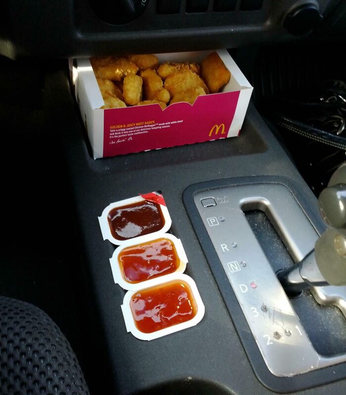 McDonald's sauces perfectly aligned next to a gear shift lever inside a car, capturing a satisfying moment of things aligned.