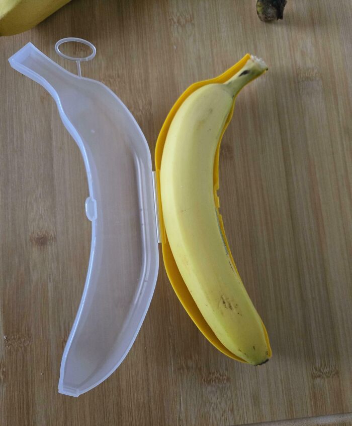 Banana perfectly aligned inside a yellow plastic case on a wooden surface, illustrating perfect alignment moments.