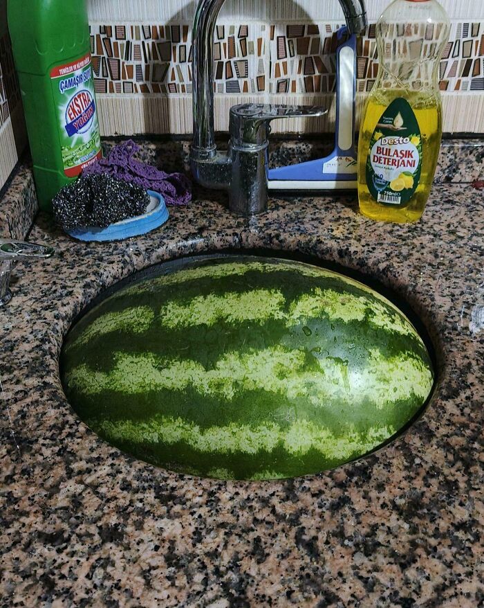 Watermelon perfectly aligned with kitchen sink creating a seamless illusion of things aligned so perfectly.