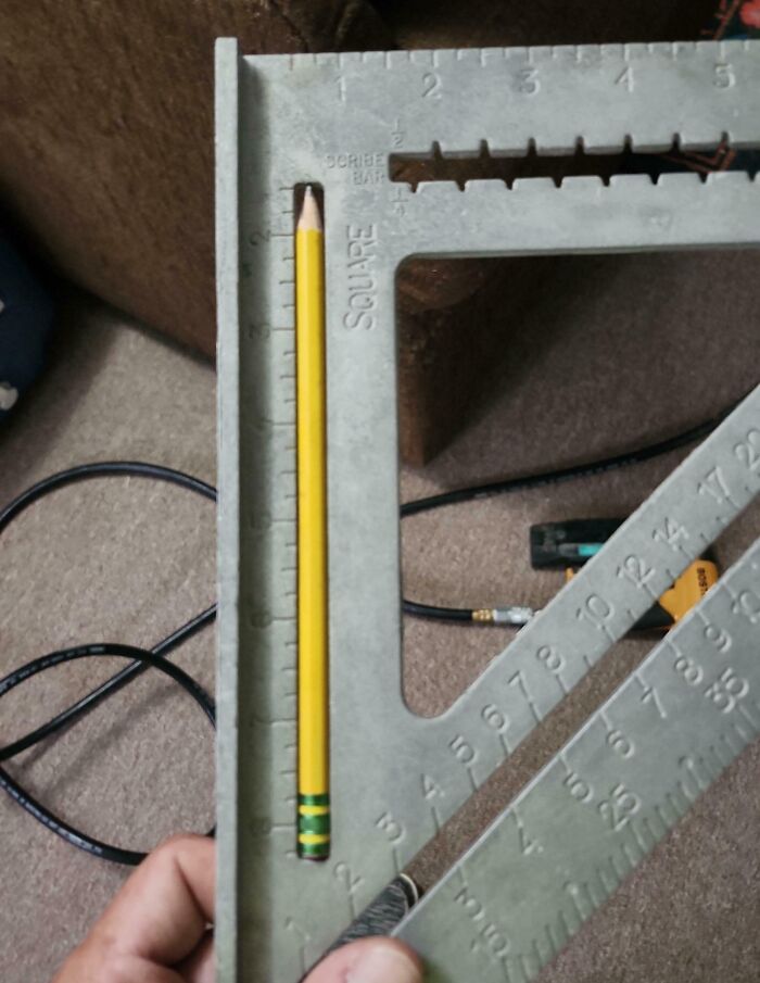 Yellow pencil perfectly aligned inside a metal square ruler, demonstrating precise measurement and perfect alignment.