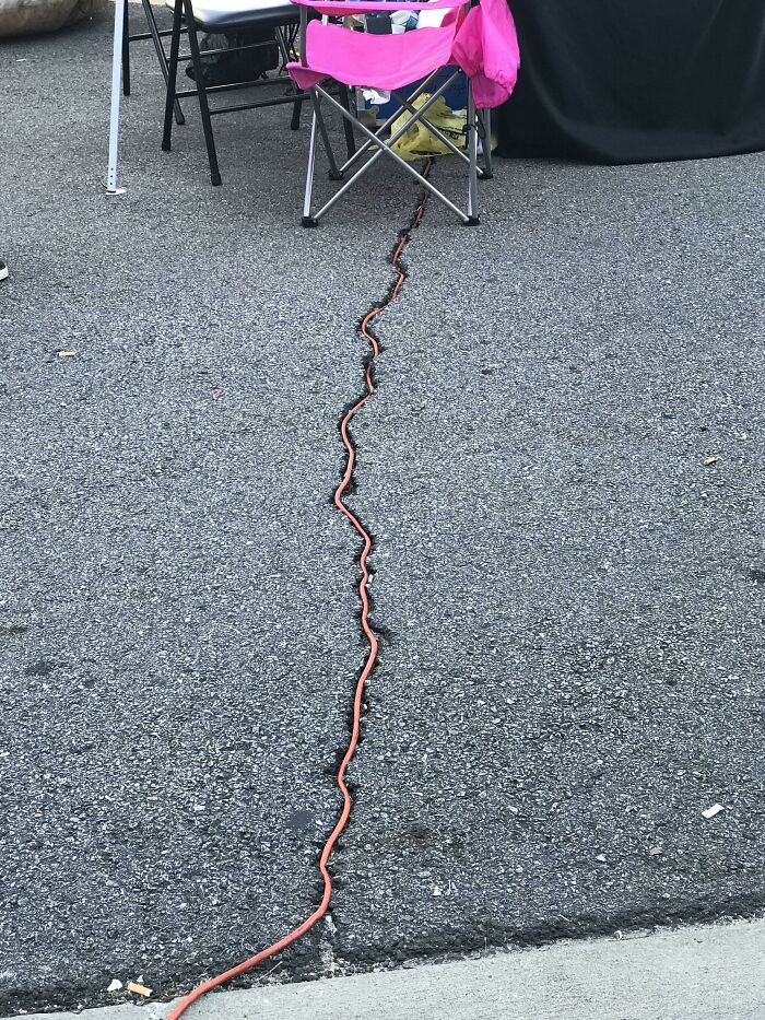 Orange cable perfectly aligned along the edge of the curb and asphalt, creating a visually satisfying scene of alignment.