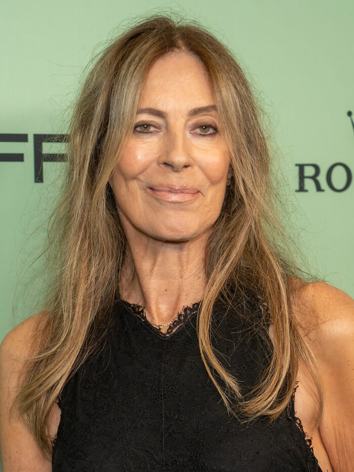 Kathryn Bigelow smiling at an event, wearing a black lace top with long, light brown hair.