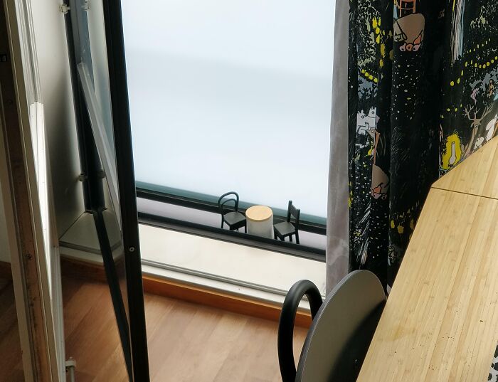 Two small chairs perfectly aligned facing each other with a round table in minimalistic indoor space.