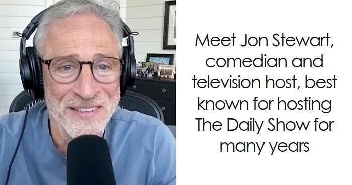Jon Stewart smiling during a virtual interview, wearing glasses and headphones with a microphone in front.