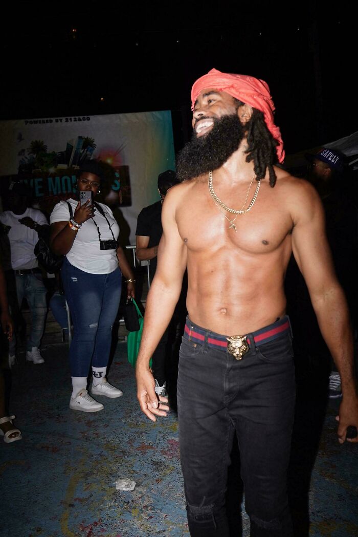 Shirtless man with beard and red headwrap smiling at night, capturing the strength and diversity of humans.
