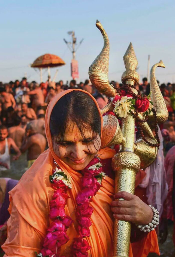 Woman in traditional attire holding decorated ceremonial staff during cultural festival celebrating human diversity and strength
