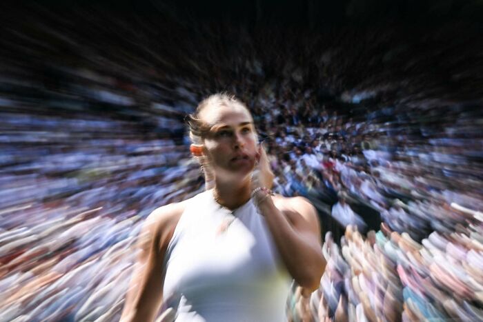 Portrait of a focused woman in a white top with blurred crowd in the background capturing human beauty and strength.
