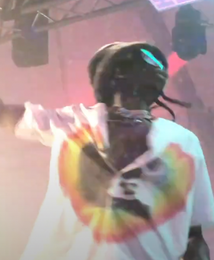 Lancey Foux performing on stage wearing a colorful graphic shirt and a beanie under stage lighting.