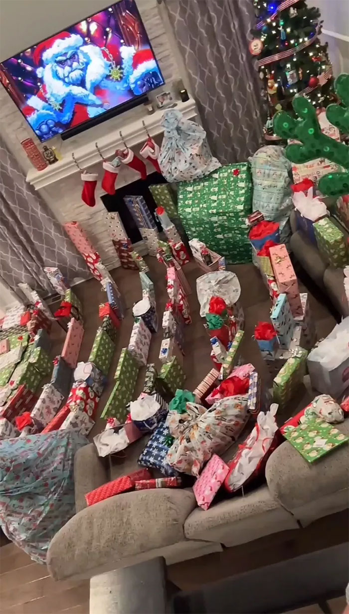 Living room filled with an insane amount of wrapped gifts for kids, highlighting consumerism during the holiday season.