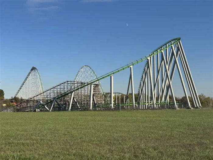 Roller coaster with 205-foot drop at an amusement park on a clear day with green grass and blue sky.