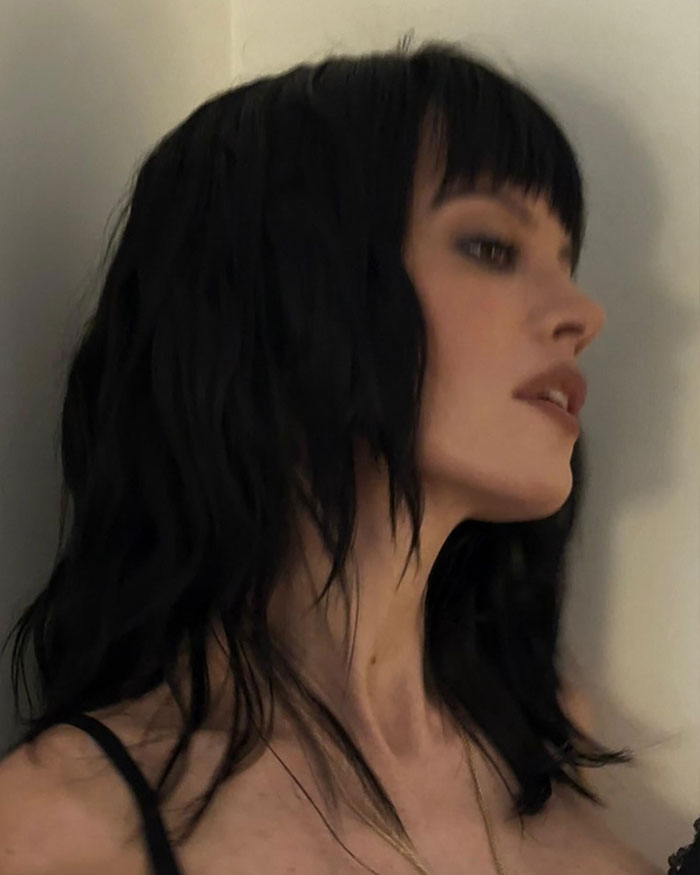 Lily Allen with dark hair and bangs posing in a black outfit, sparking debate online over her CFDA fashion look.