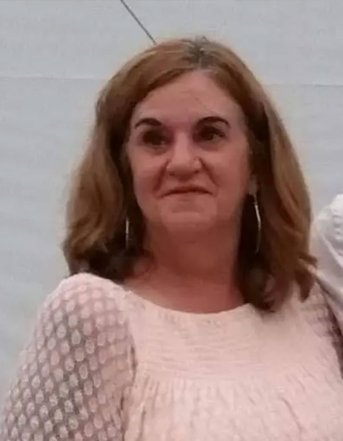 Woman linked to missing woman’s body discovered in garage case, posing indoors with light-colored top and hoop earrings.