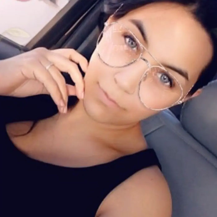 Woman wearing large glasses sitting in a car, related to broken mother learning fate after slaying young sons story. Woman wearing large glasses sitting in a car, related to broken mother learning fate after slaying young sons story.