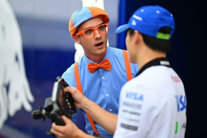 Actor dressed as Blippi wearing an orange bow tie and cap talking to a man holding a camera remote control. Actor dressed as Blippi wearing an orange bow tie and cap talking to a man holding a camera remote control.
