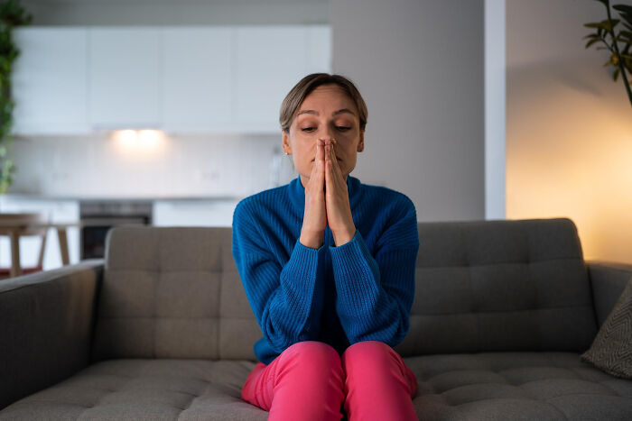 Woman sitting on a couch looking distressed, illustrating emotional signs a child was never loved properly.