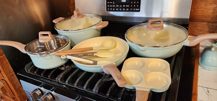 Set of pastel cookware including pots, pans, and utensils on a stove, perfect for holiday gift satisfaction ideas.