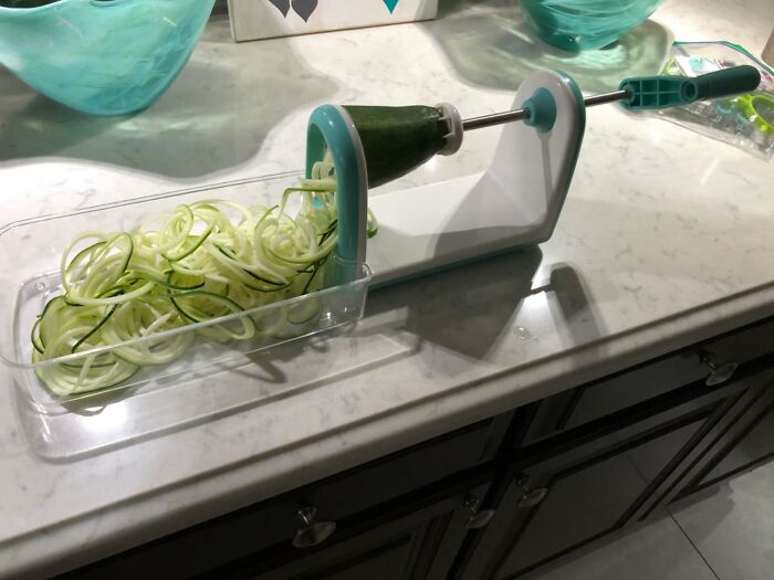 Spiralizer slicing zucchini into noodles on a white kitchen counter, showcasing a viral product trending on TikTok.