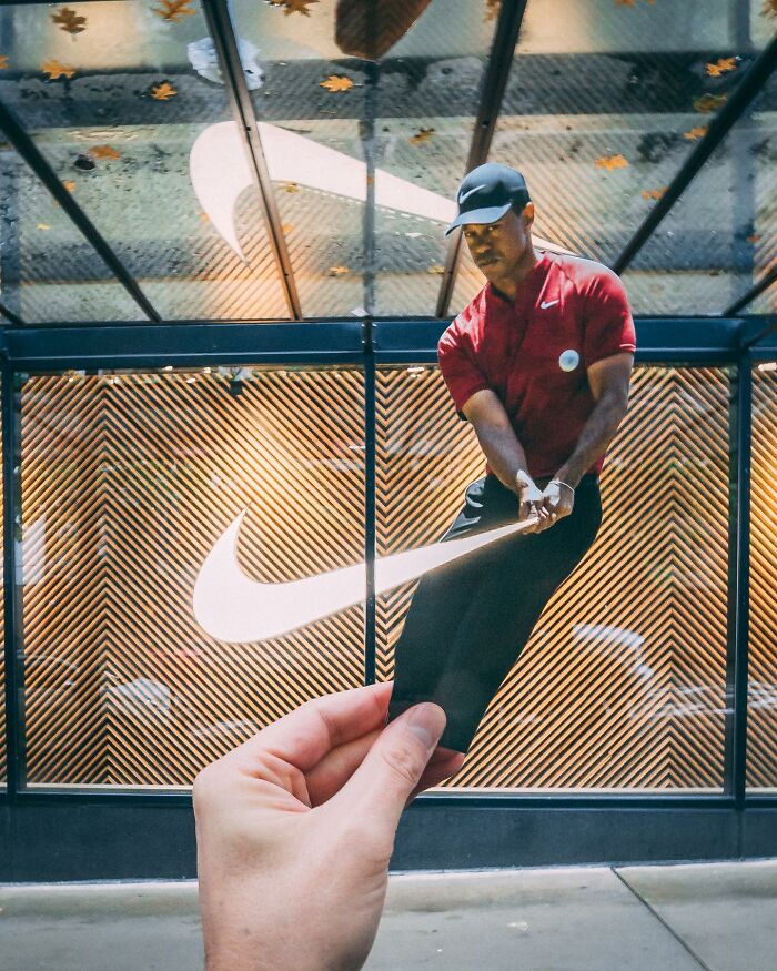 Hand holding paper cutout of golfer with a Nike logo interacting with real-life background in creative paper cutouts.