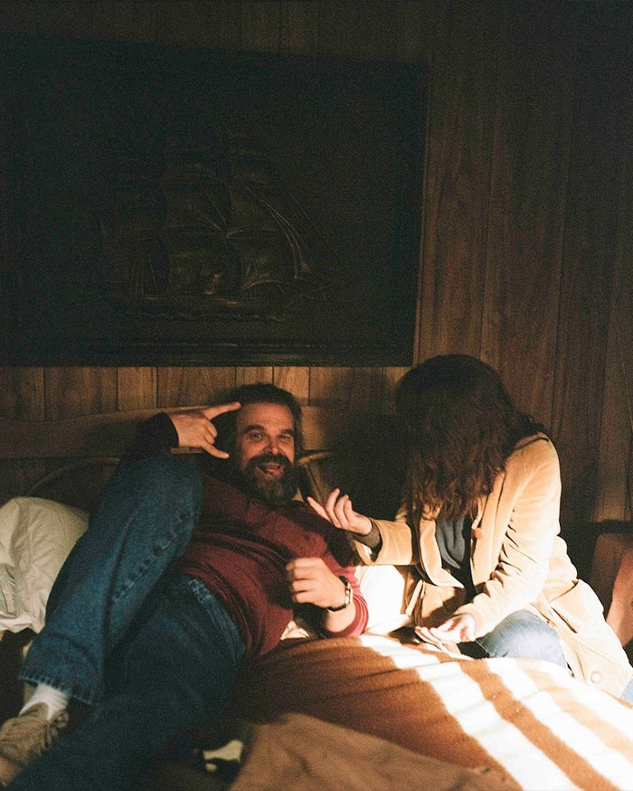 David Harbour relaxing indoors with a woman, highlighting Stranger Things co-star connection in a cozy setting. David Harbour relaxing indoors with a woman, highlighting Stranger Things co-star connection in a cozy setting.