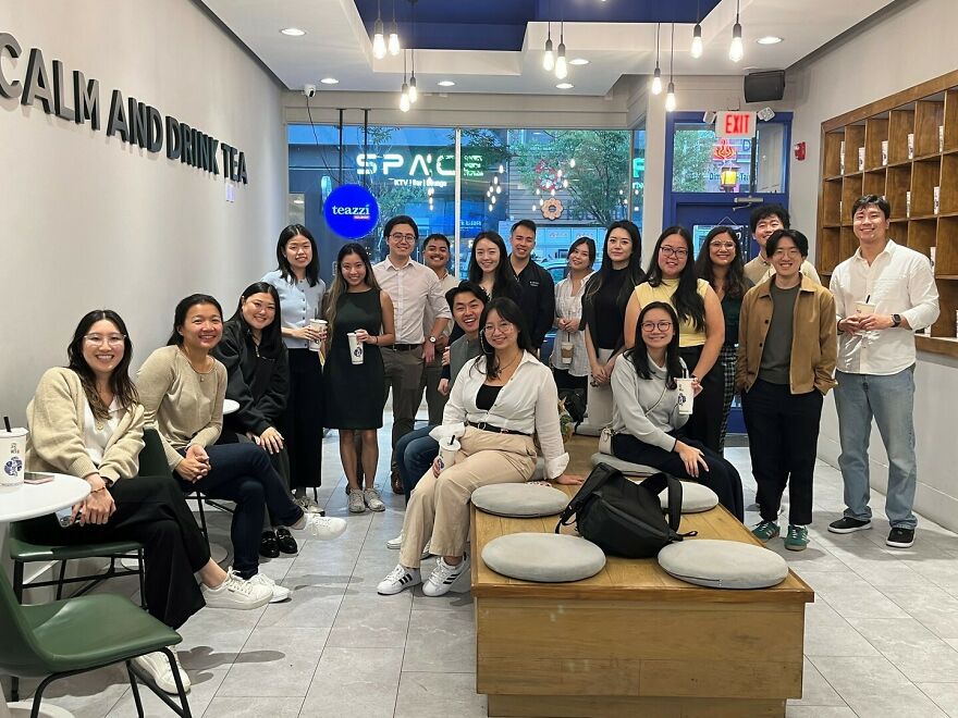 Group of diverse young adults smiling and socializing in a modern tea shop, promoting awareness of Asian stereotypes.