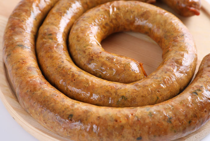 Close-up of a coiled sausage on a wooden plate, humorously contrasting with funny patients’ comments in hospitals.