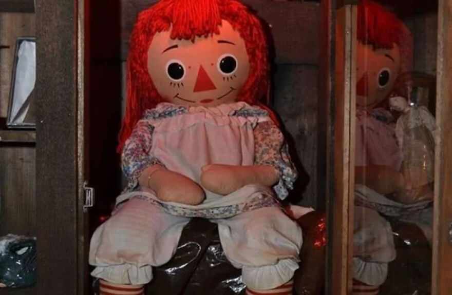 Annabelle doll with red hair and white dress displayed in wooden cabinet relating to Matt Rife’s net worth and purchases. Annabelle doll with red hair and white dress displayed in wooden cabinet relating to Matt Rife’s net worth and purchases.