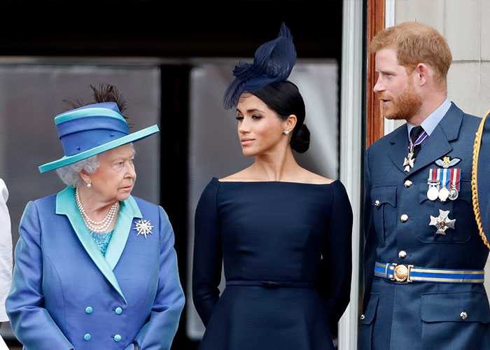 Meghan Markle in a navy dress and fascinator with Queen Elizabeth II and Prince Harry at a formal public event. Meghan Markle in a navy dress and fascinator with Queen Elizabeth II and Prince Harry at a formal public event.