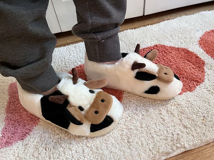 Person wearing novelty cow slippers on a rug, showcasing one of the most fun and unnecessary novelty finds.