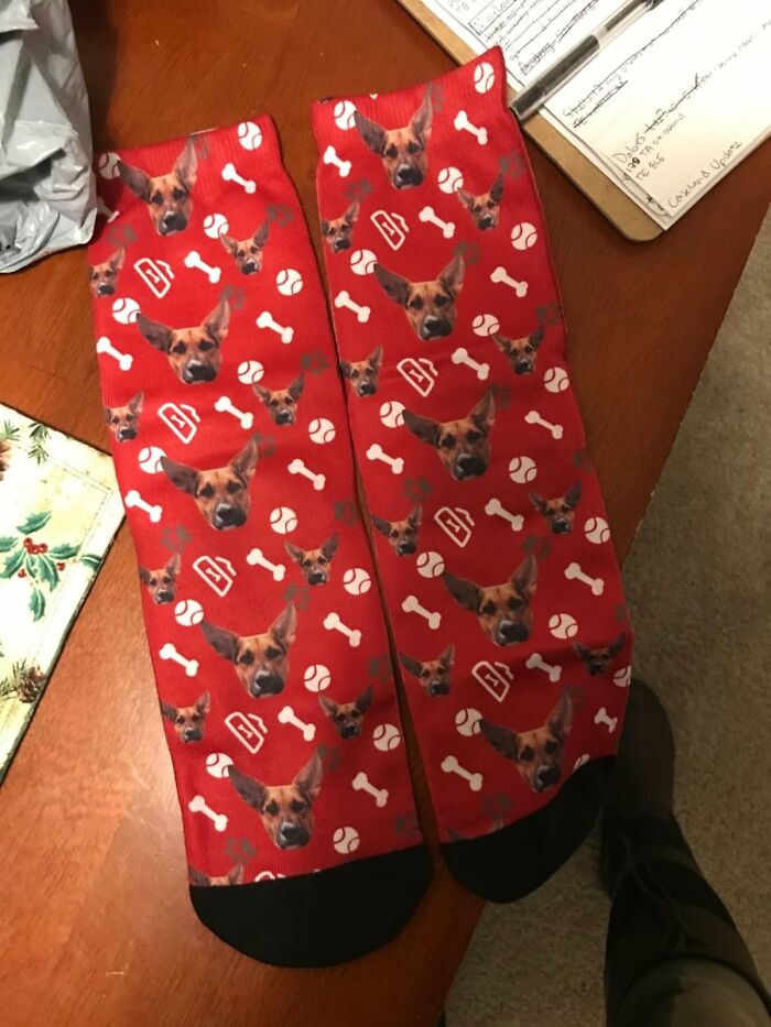 Red socks with dog faces, bones, and baseballs pattern, a unique gift idea for people who are impossible to shop for.