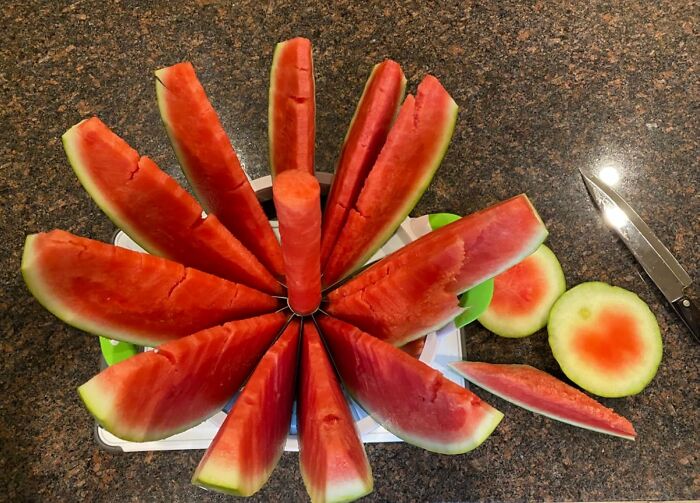 Watermelon sliced evenly using a kitchen find on a granite countertop with a knife nearby
