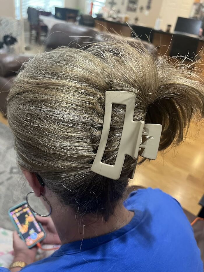 Person with a beige hair claw clip holding phone, representing a cozy burr basket starter kit for hibernating until spring.